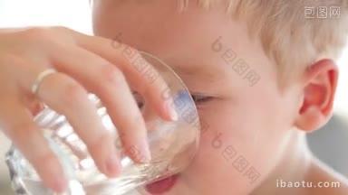 可爱的小男孩喝着一杯新鲜的水，他的母亲拿着他解渴